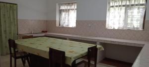 eine Küche mit einem Tisch und Stühlen sowie 2 Fenstern in der Unterkunft Coconut Breeze Villa in Mirissa