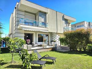 a large house with a yard with chairs in front of it at Modern Villas at Perla Resort in Durrës +126 photos