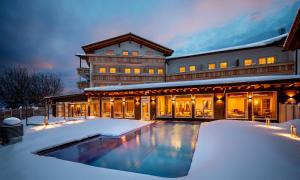 une maison avec une piscine dans la neige dans l'établissement Hanusel Hof Wellness & Genuss in Panoramalage, à Hellengerst
