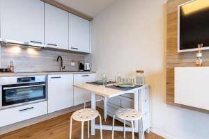 una cocina con armarios blancos, mesa y taburetes en Remointze B 031 - CENTER studio 4 pers, en Veysonnaz 5 fotos más
