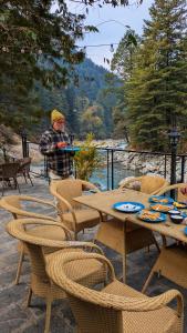 a man standing on a patio with tables and chairs at La Familia Kasol in Kasol