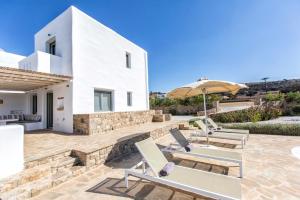 Casa blanca con patio con sillas y sombrilla en Glyfada's Villa, en Kastraki Naxou