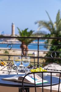 two wine glasses sitting on a table on a balcony at Chryssi 01, Stylish Seaside Spot in the Heart of Rethymno in Rethymno Town