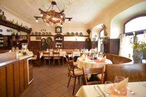a restaurant with tables and chairs and a chandelier at AKZENT Hotel Grüner Baum Check in Kiosk vorm Hotel in Dettelbach