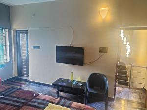 Una sala de estar con una mesa y un televisor en la pared. en Nainika home stay way to Isha and marudhamalai, en Coimbatore