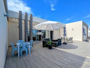 a patio with tables and chairs and an umbrella at Wonderful villa rental with swimming pool in Arkou