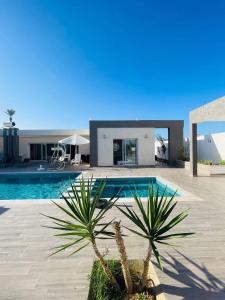 a swimming pool with two palm trees in front of a house at Wonderful villa rental with swimming pool in Arkou