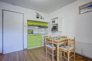 a kitchen with green cabinets and a table and chairs at Le Petit Montagnard - Station accessible à pied in Les Angles +4 photos