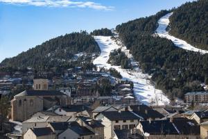a town with a snow covered mountain and a ski slope at Le Petit Montagnard - Station accessible à pied in Les Angles