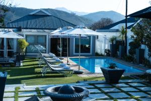 a backyard with a pool and chairs and umbrellas at LA RÉVERIE in Franschhoek