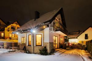 a house with lights in the snow at night at Wichrowe Zacisze 2 in Krynica Zdrój