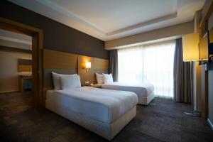 a hotel room with two beds and a window at Boyalik Beach Hotel & Spa Cesme in Çeşme
