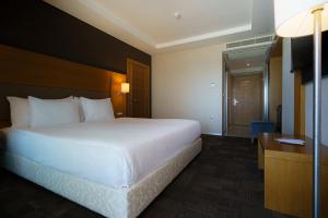 a hotel room with a large bed and a desk at Boyalik Beach Hotel & Spa Cesme in Çeşme
