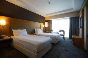 a hotel room with two beds and a desk at Boyalik Beach Hotel & Spa Cesme in Çeşme