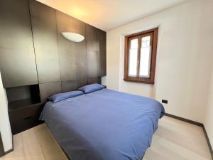 1 dormitorio con cama azul y ventana en White Nest Apartment, en Ponte di Legno