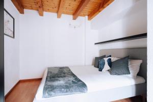 アオスタにあるAosta Holiday Apartments - Mailletの白いシーツと木製の天井のベッドのある寝室