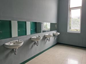 a bathroom with three sinks and a window at Populair Hostel Braga in Bandung