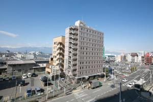 ein hohes weißes Gebäude in einer Stadt mit einer Straße in der Unterkunft Ace Inn Matsumoto in Matsumoto