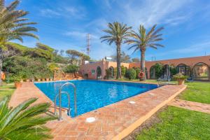 a swimming pool in a yard with palm trees at Hurricane Beach Hotel in Tarifa