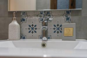 a bathroom sink with a faucet and a bottle of soap at Melina's Studios in Argalasti +19 photos