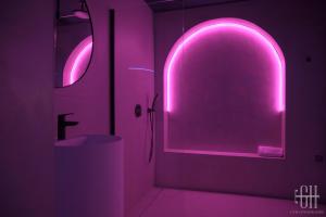 ein Bad mit einer rosa beleuchteten Tür und einem Waschbecken in der Unterkunft La Favorite - Love-Room Sensuelle in Amboise + 27 Fotos