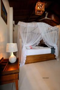 Florain Otium Talpe - 3 Bedroom Oceanfront Villa في يوناواتونا: غرفة نوم بسرير مع طاولة مع مصباح