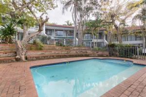 a swimming pool in front of a house with trees at Unit 4 Springvale in Zinkwazi Beach