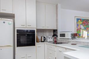 a kitchen with white cabinets and a black appliance at Unit 4 Springvale in Zinkwazi Beach
