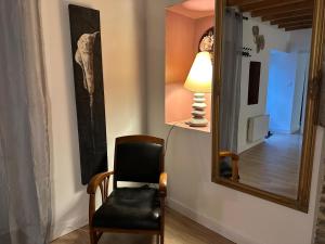 einen Stuhl und eine Lampe in einem Zimmer mit Spiegel in der Unterkunft Évasion à Hainneville in Cherbourg en Cotentin + 14 Fotos