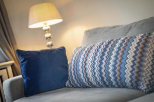 a couch with two blue pillows next to a lamp at Litz Hues in Keitum