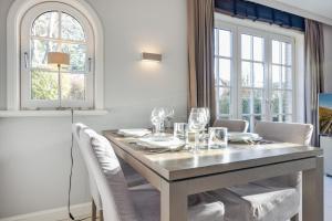 a dining room with a table and chairs and windows at Litz Hues in Keitum