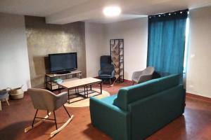 a living room with a couch and chairs and a tv at Gîte de Briante in Saint-Lager