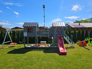 a playground with a slide and a play house at WAKACYJNE ZAGAJE in Sarbinowo