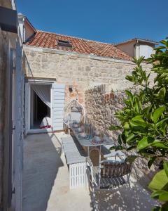 a stone house with a table and chairs on a patio at Orange Tree House in Vis
