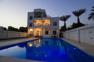 a house with a swimming pool in front of a house at Villa Abo Tarek in Al Aqālitah