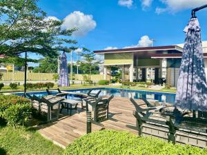 - une piscine avec des chaises, une table et un parasol dans l'établissement Llames Studios Near Mactan Airport - Rustic & Spacious, à Lapu Lapu City