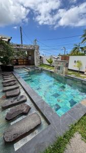 a swimming pool with rocks in a yard at Blue Naiade Villa zen and cosy in Étang-Salé