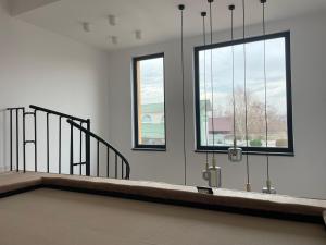 a room with two windows and a stair case at Primaverii 10 by GIA in Caracal
