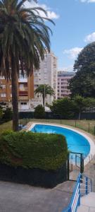 a swimming pool with a palm tree and a building at Castro-urdiales Apartamento 3 minutos de la playa in Castro-Urdiales