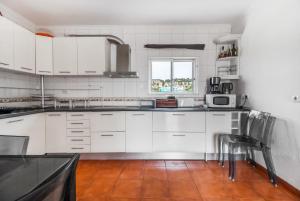 a white kitchen with white cabinets and a window at Saude Beach House in Costa da Caparica +11 photos