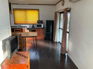 a kitchen with a table and a tv in a room at こにべ 平屋庭付き一棟貸し 棟脇駐車静かで便利なスーパー3分 in Miyazaki