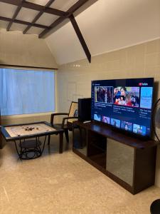 a room with a table and a large screen television at Thanjee Homestay Family Cottage in Yelagiri