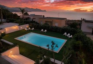 a backyard with a swimming pool and chairs and the ocean at Oasi Elegante Piscina di Lusso - vista panoramica By Sicily Home Solutions in Alcamo
