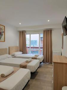 une chambre d'hôtel avec trois lits et une télévision dans l'établissement Pensión Portugal, à Alicante 97 autres photos