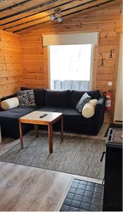 Sala de estar con sofá negro y mesa de centro en North Frontier 1-bedroom cabin, en Saariselkä