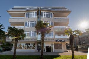 budynek z palmami przed nim w obiekcie Primera Linea de Playa Samil Costa con Garaje Incluido w mieście Vigo