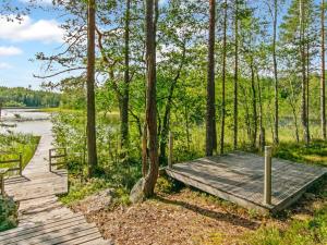 een houten vlonder naast een meer met bomen bij Holiday Home Karhupirtti by Interhome in Mäntyharju