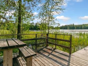 een houten bank op een steiger bij een waterpartij bij Holiday Home Karhupirtti by Interhome in Mäntyharju