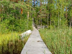 een houten pad door een moeras met een boot erop bij Holiday Home Karhupirtti by Interhome in Mäntyharju +23 foto's