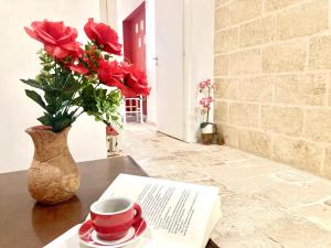 a vase of roses and a cup of coffee on a table at Antica Pietra in Polignano a Mare +37 photos